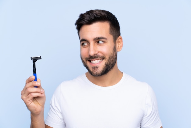 Homme avec lame de rasoir sur mur bleu isolé