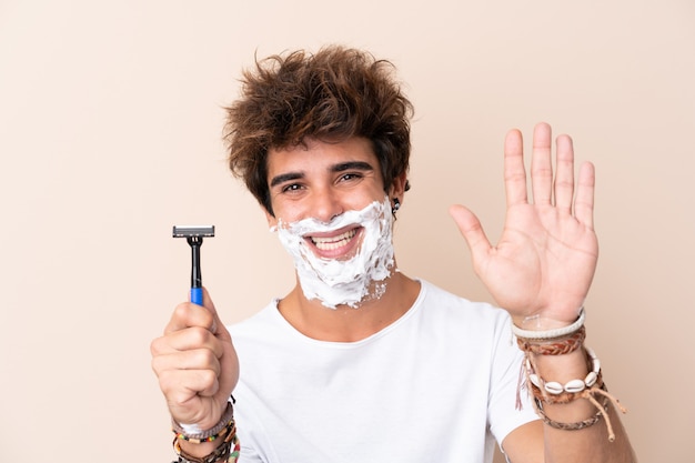 Photo homme avec lame de rasoir sur mur isolé