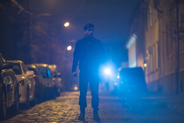 L'homme avec une lampe de poche se tient dans la rue. Le soir la nuit