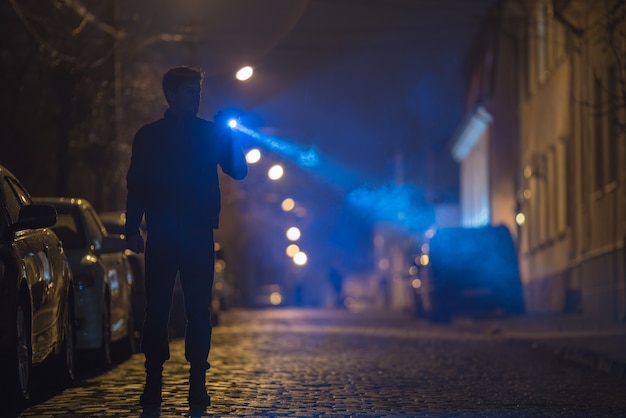 L'homme avec une lampe de poche se tient sur la route. Le soir la nuit