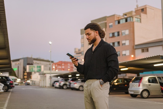 Homme latin d'affaires avec un téléphone dans un parking