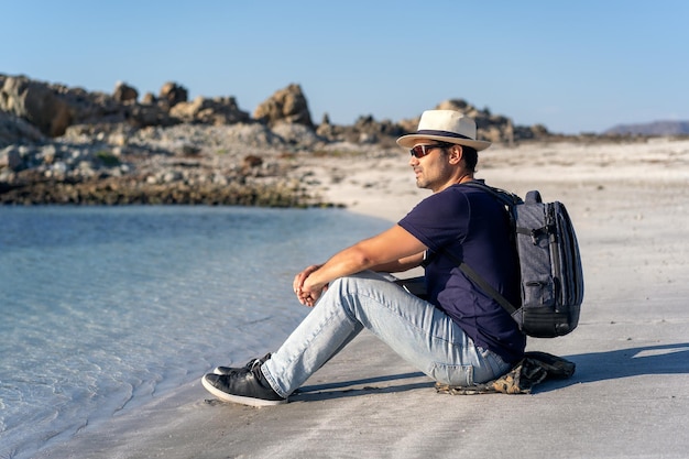 Homme latin assis sur la plage au coucher du soleil