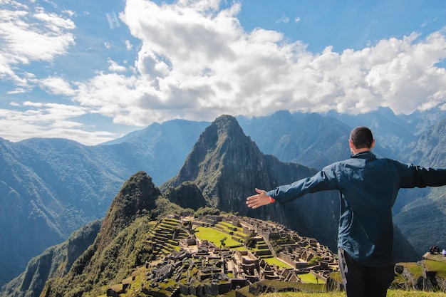 Homme latin inconnu sur la montagne à bras ouverts regardant le Machu Picchu Pérou