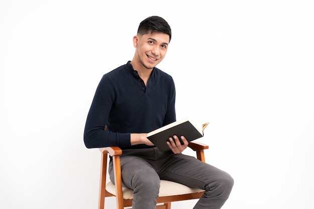 Homme latin avec livre en mains souriant à la recherche