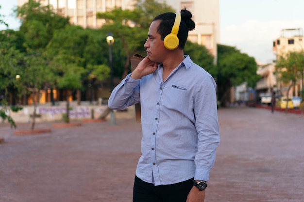 Homme latino avec des écouteurs écoutant de la musique dans le parc