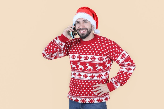 Homme latino hispanique avec chapeau de Noël à l'aide d'un téléphone portable