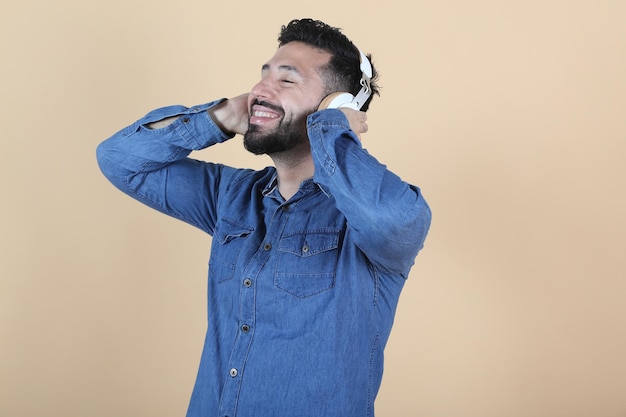 Homme latino hispanique détendu écoute de la musique avec des écouteurs sur fond jaune