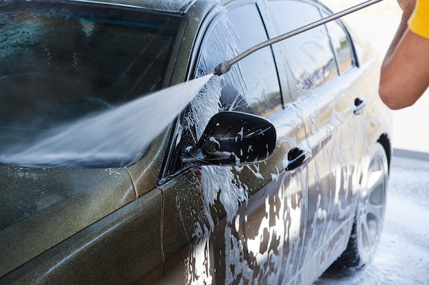 Un homme lave sa voiture avec de l'eau