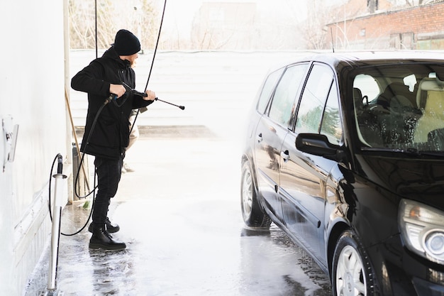 L'homme lave sa voiture sur le lave-auto express en libre-service