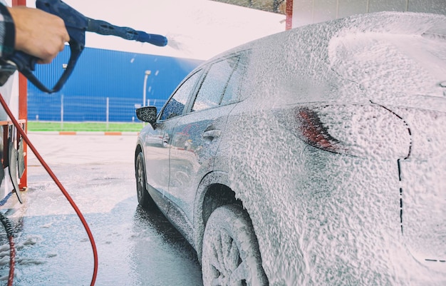 Photo l'homme lave sa voiture sur le lave-auto en libre-service