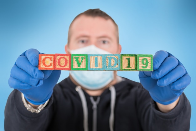 Homme avec lettre de cubes en bois avec le COVID 19 écrit