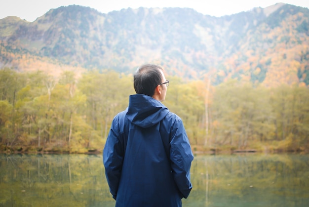 Homme de la liberté se tenir au bord du lac contre les montagnes et la forêt d&#39;automne naturelle