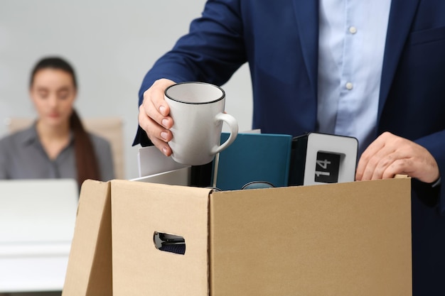 Homme licencié emballant des affaires personnelles dans une boîte en gros plan de bureau