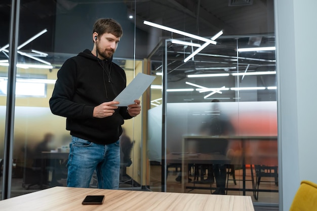 Homme lisant un document avec des statistiques travaillant sur un rapport au bureau