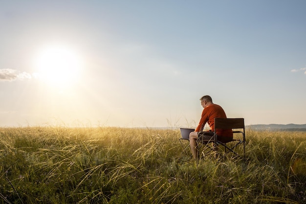 homme lisant un e-mail sur un ordinateur portable avec Internet 5G tout en travaillant par nature estivale au coucher du soleil travail à distance