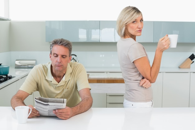 Homme lisant un journal et une femme avec une tasse de café