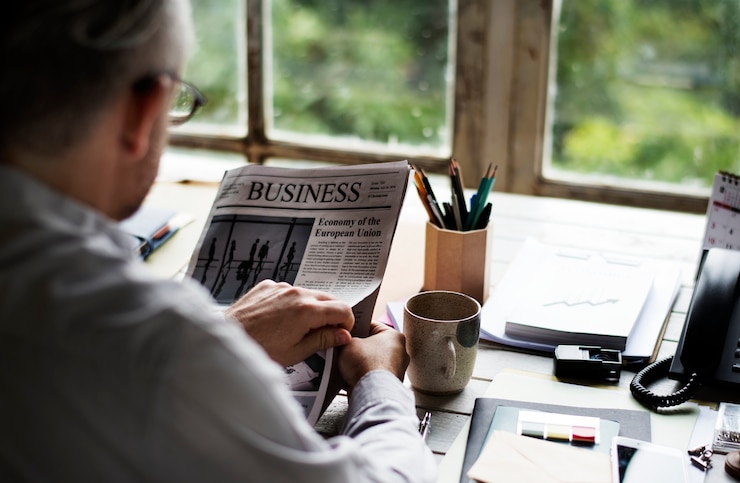 Photo homme lisant un journal à son bureau