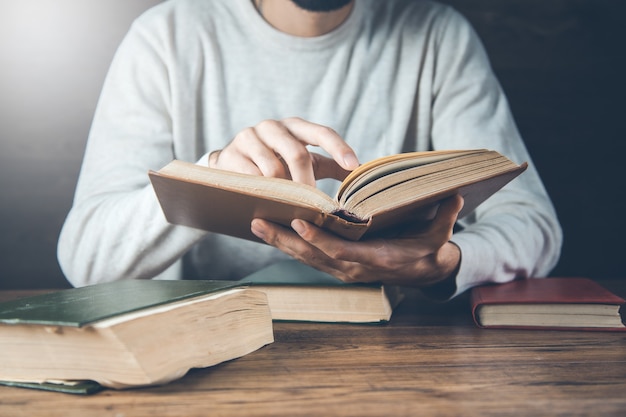 Homme lisant un livre sur le bureau en bois