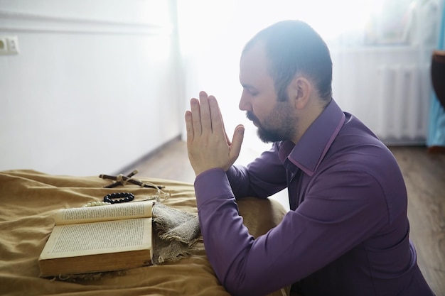 Homme lisant et priant de la sainte bible près du lit le soir. Chrétiens et concept d'étude de la Bible. Étudier la Parole de Dieu à l'église.