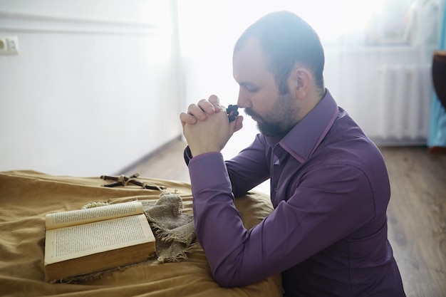 Homme lisant et priant de la sainte bible près du lit le soir Chrétiens et concept d'étude biblique Étudier la Parole de Dieu à l'église