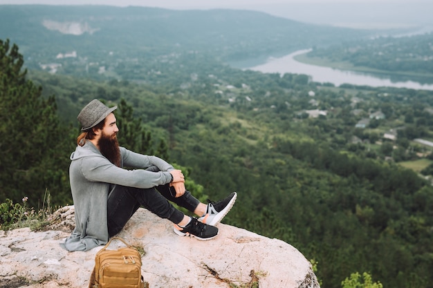 Homme avec une longue barbe assis au sommet de la montagne