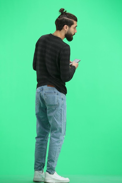 Un homme de longueur entière sur un fond vert avec un téléphone