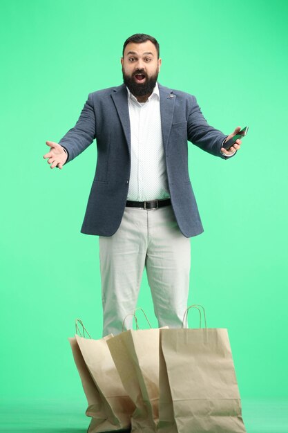 Un homme de longueur entière sur un fond vert avec un téléphone