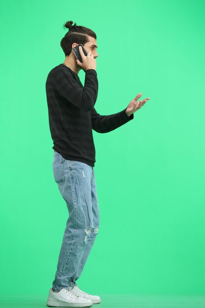 Un homme de longueur entière sur un fond vert avec un téléphone