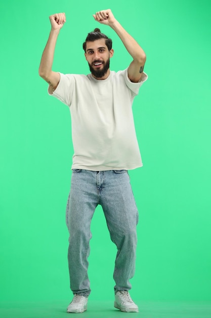 Un homme de longueur sur un fond vert a levé les mains