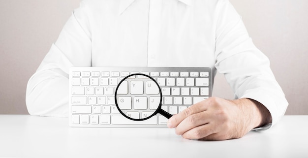 Homme Avec Loupe Et Clavier Blanc D'ordinateur Ou Ordinateur Portable