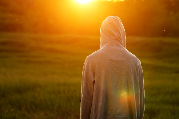 Un homme à la lumière du coucher de soleil avec ses mains levées