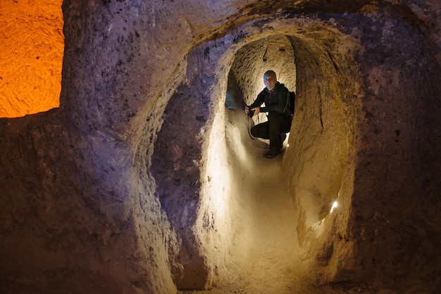 Homme avec des lumières explorant des grottes dans l'ancienne ville souterraine à plusieurs niveaux de Derinkuyu, dans la province de Nevsehir, Cappadoce, Turquie. Intérieur de la salle rocheuse.