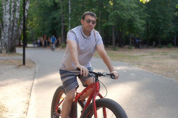 Un homme à lunettes noires fait du vélo dans un parc public Sports et loisirs