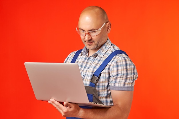 L'homme à lunettes de protection tient dans sa main et travaille sur un ordinateur portable