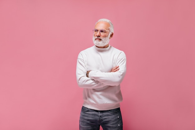 Homme à lunettes et pull posant sur un mur isolé