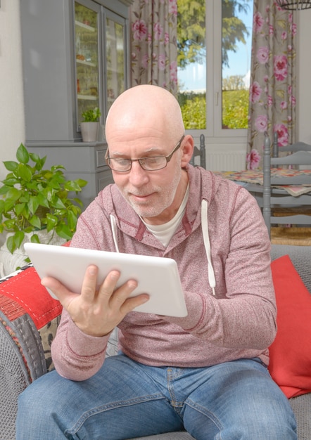 Un homme avec des lunettes en regardant une tablette