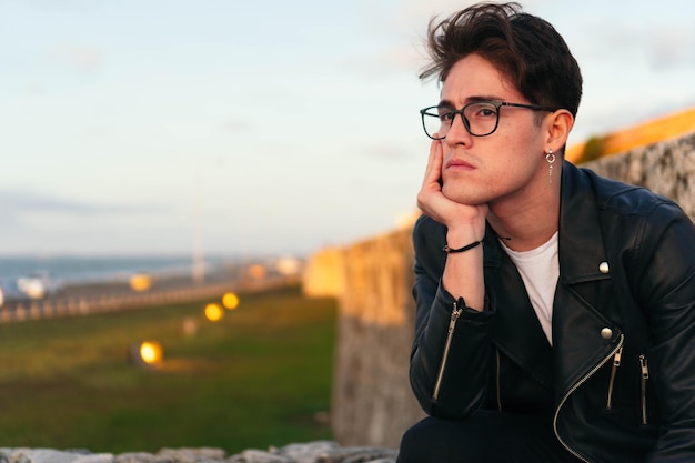 Un homme avec des lunettes s'appuyant sur la balustrade en plein air