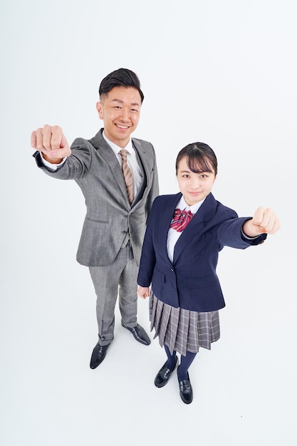 Un homme et une lycéenne en costume faisant une pose de tripes
