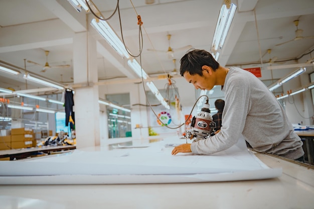 Photo homme avec machine à découper et équipement de protection individuelle sur le lieu de travail industriel du vêtement