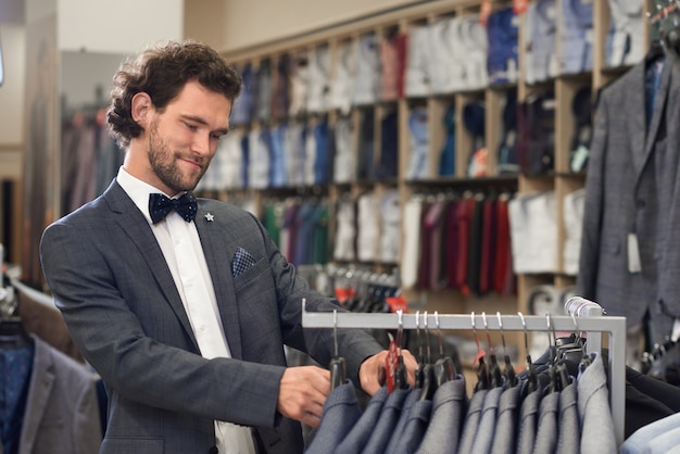 Homme en magasin à la recherche de la partie supérieure parfaite du costume.