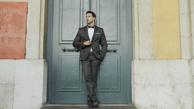 Homme magnifique en costume contre la porte vert foncé action marié ou mari en attente de la mariée