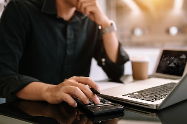 Homme de main faisant des finances et sur le bureau au sujet du coût au bureauxA