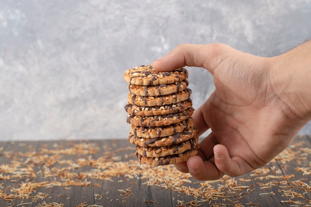 Homme main tenant une pile de biscuits à l'avoine sur une table en pierre.