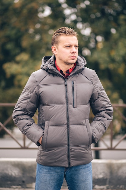 Un homme avec les mains dans les poches dans une veste d'hiver à l'extérieur