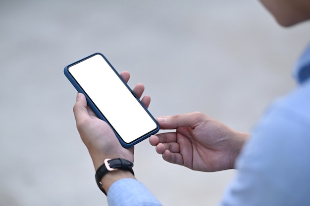 Un homme mains tenant un téléphone intelligent avec écran vide pour votre message texte ou contenu d'information.