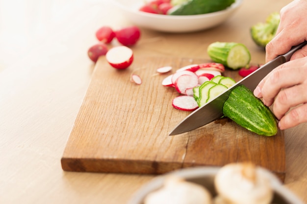 Homme mains tranches de légumes pour la cuisson des aliments végétariens