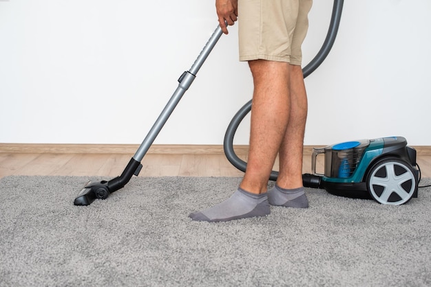 Un homme à la maison choisit exactement quelle brosse attacher à l'aspirateur