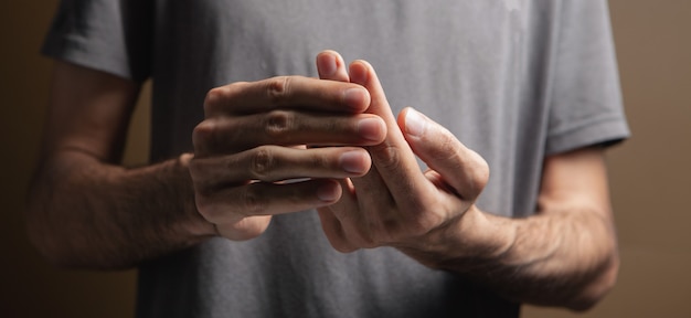 L'homme a mal au doigt sur fond gris