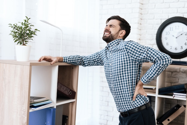 L&#39;homme a mal au dos. Il garde ses mains sur la taille.