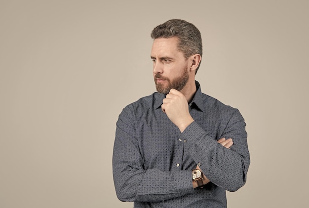 Un homme mal rasé avec une forme de cheveux de barbe élégante a l'air sérieux dans un espace de copie de chemise de style décontracté